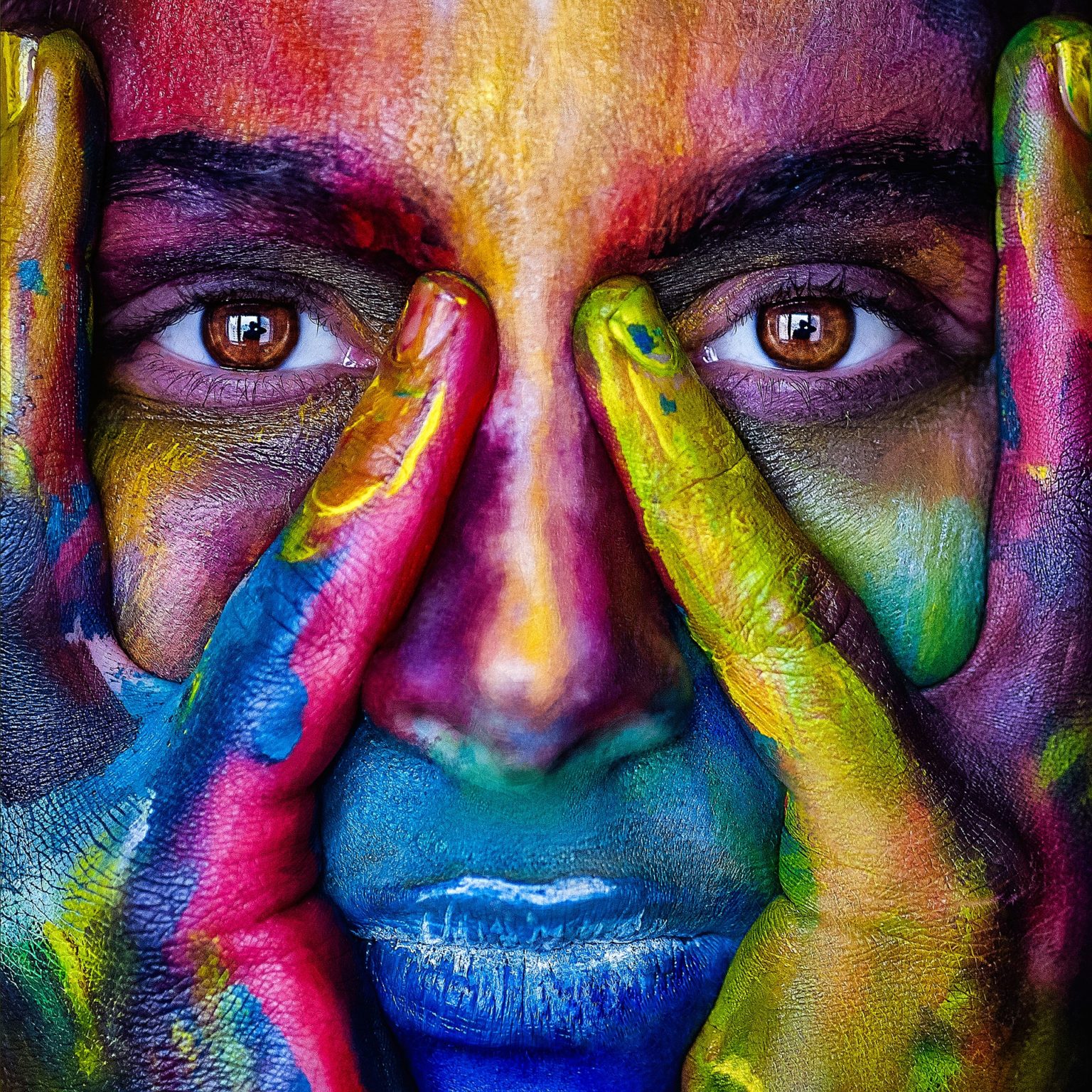 close-up face covered in different coloured paint
