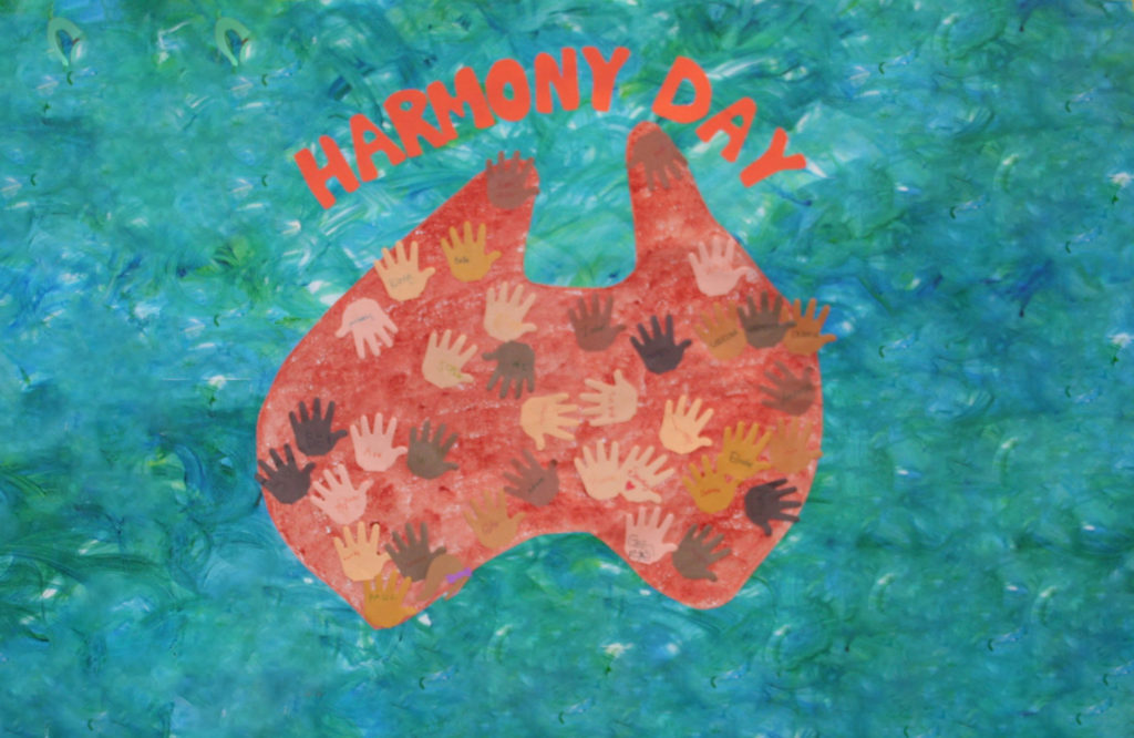 artwork saying "harmony day" with an image of Australia covered in multicoloured handprints