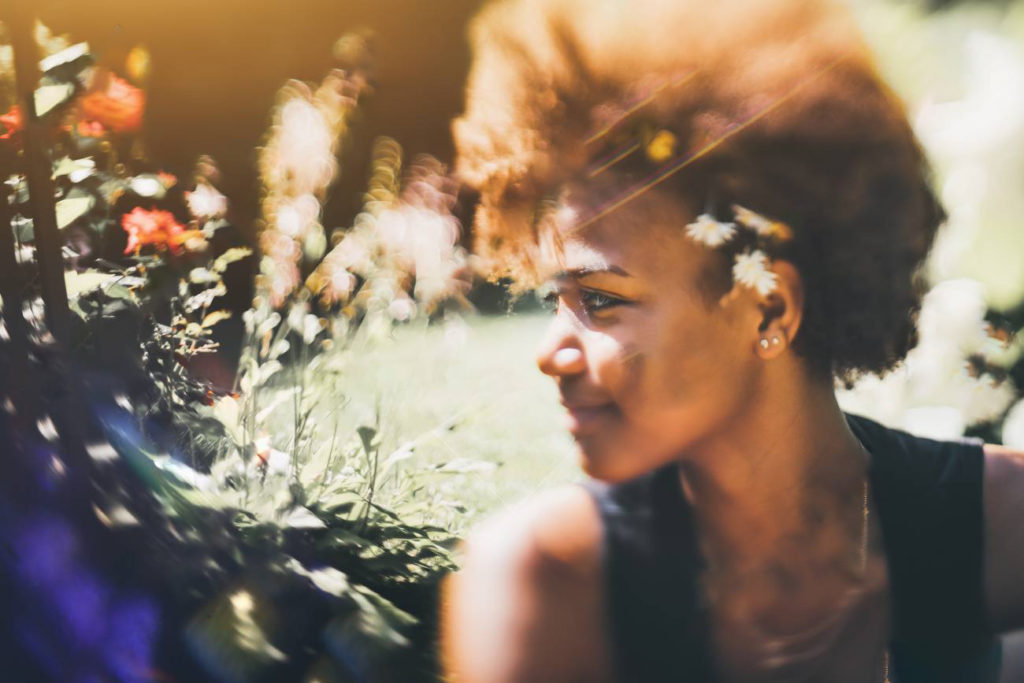 a woman with a short afro and daisies tucked behind her ear