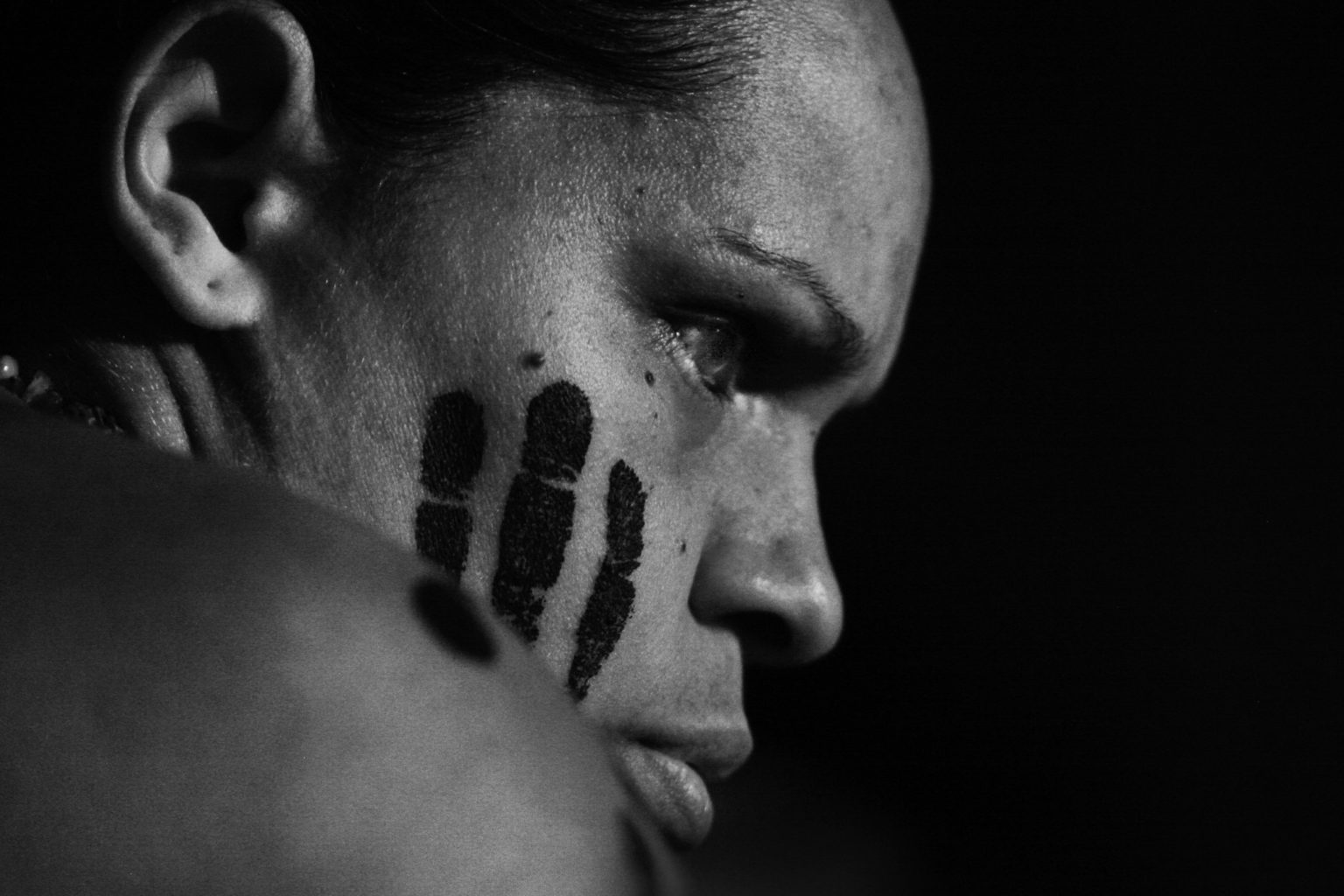 photo in profile of a person with three black marks on their face