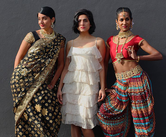 a trio of women - first in a sari, second in a white tiered dress, third in choli and wide pleated pants