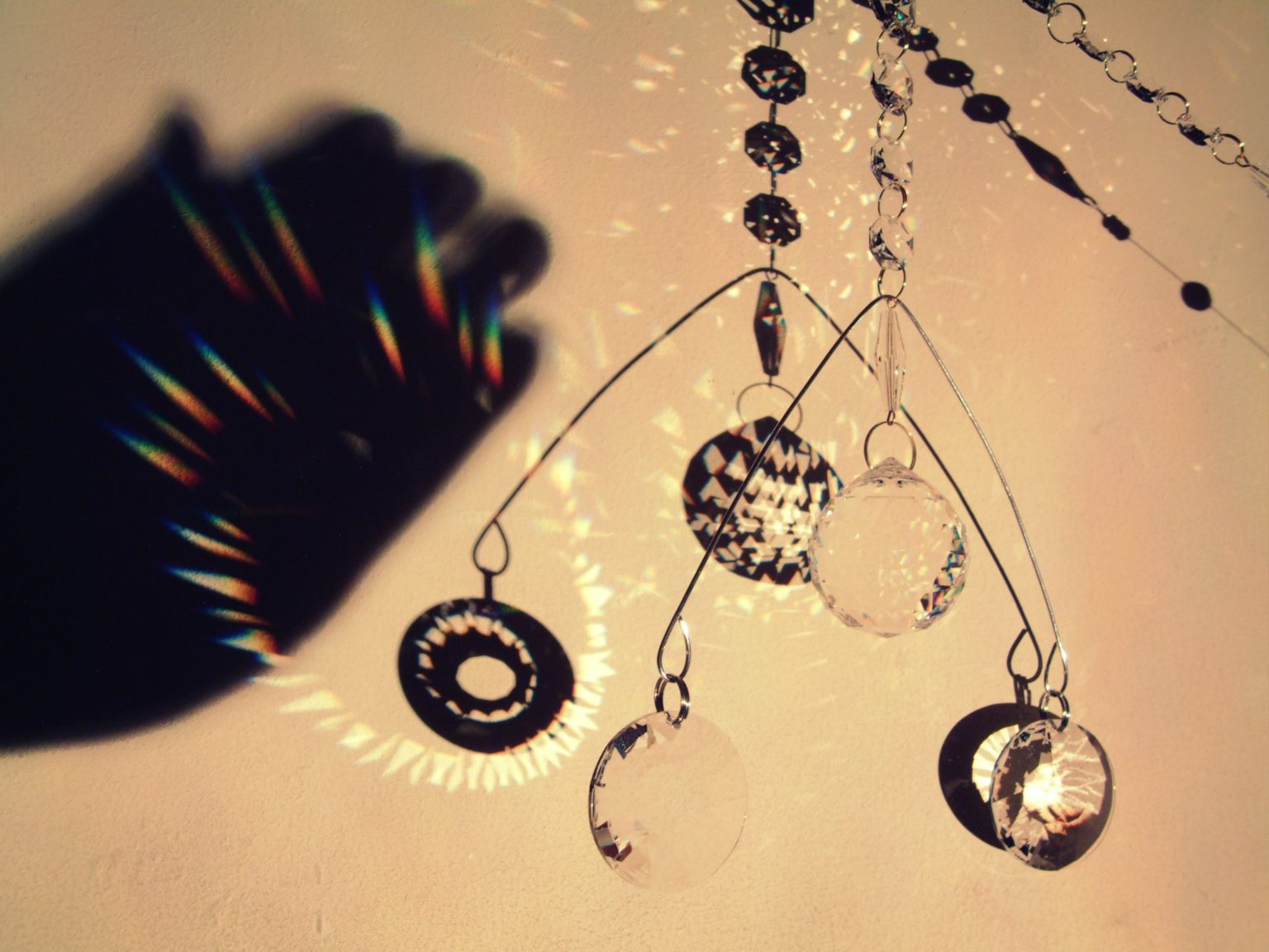 a mobile of crystals casts rainbow patterns onto a wall