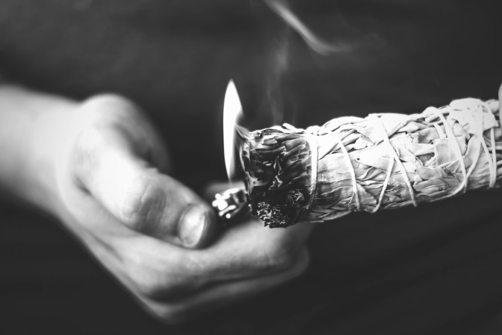 a hand lighting a stick of sage