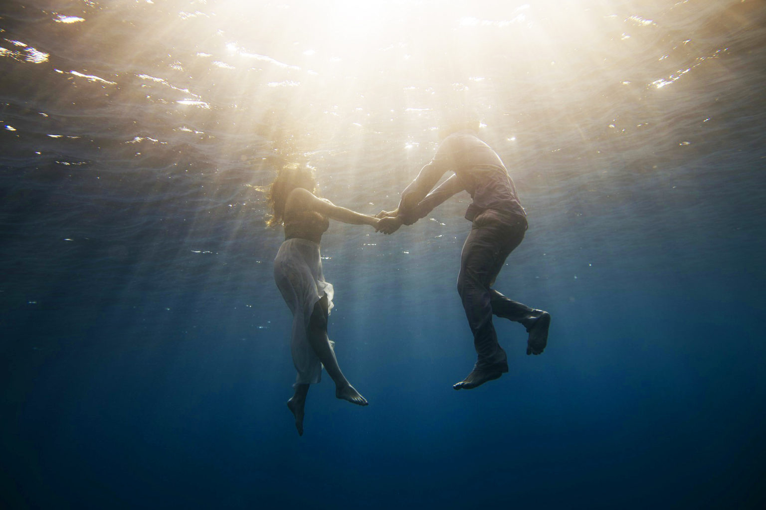 two people holding hands underwater