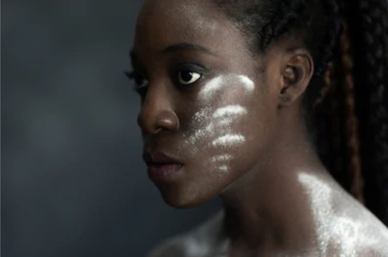a dark-skinned woman facing to the left with white powder marks on her face