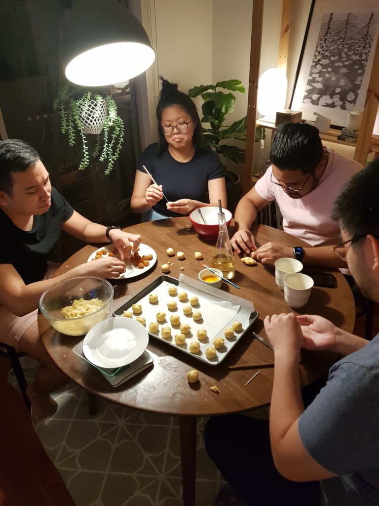 four people around a kitchen table, making pig-shaped dumplings