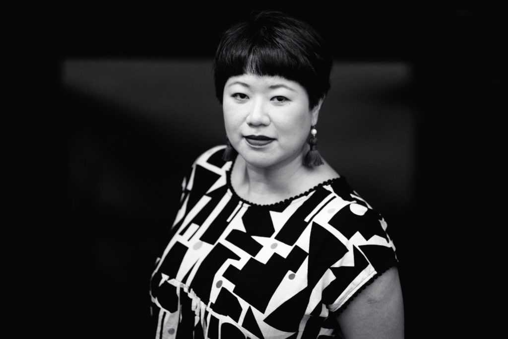 Eileen Chong looking at the camera, wearing tassel earrings and a graphic print top