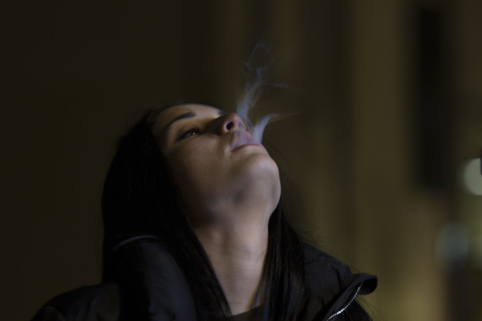 person leaning back, blowing out smoke