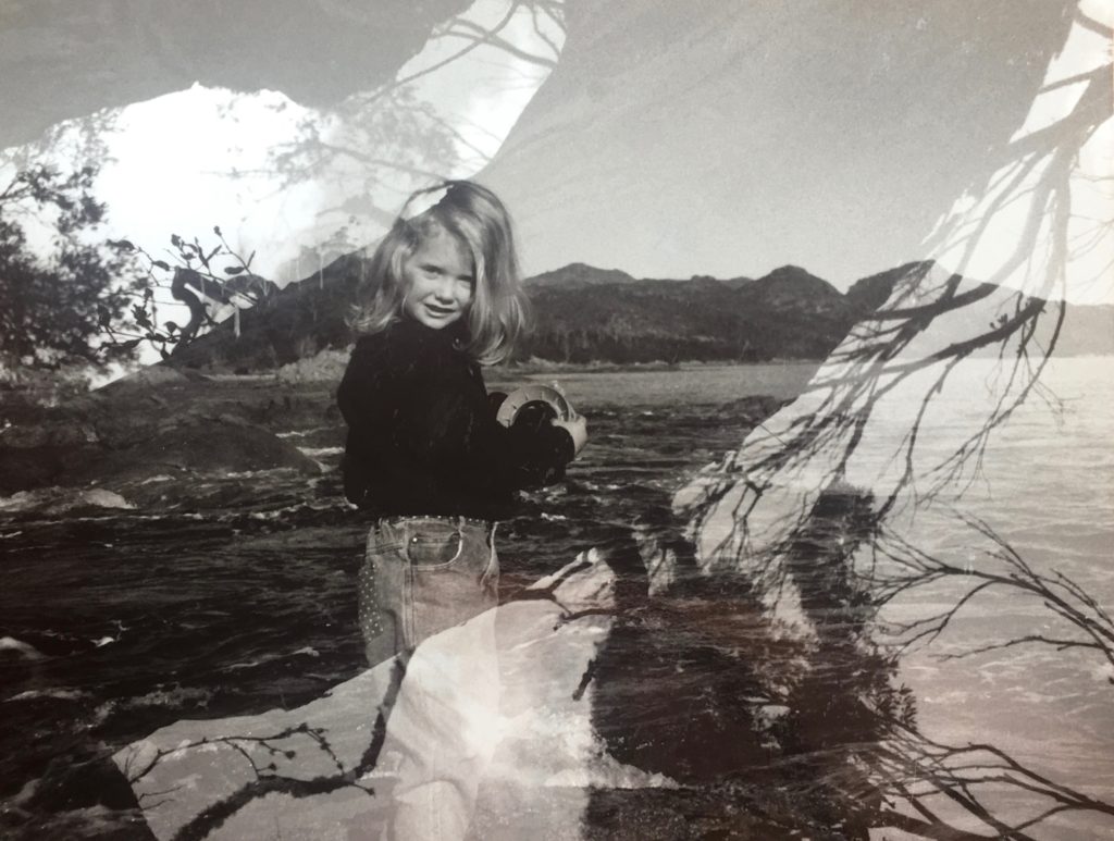 A double exposed image of Neika Lehman as a child, against a landscape with mountains and tree branches