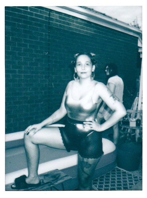 Ana Maria Gomides in a shiny leotard and shorts, with fluffy slides