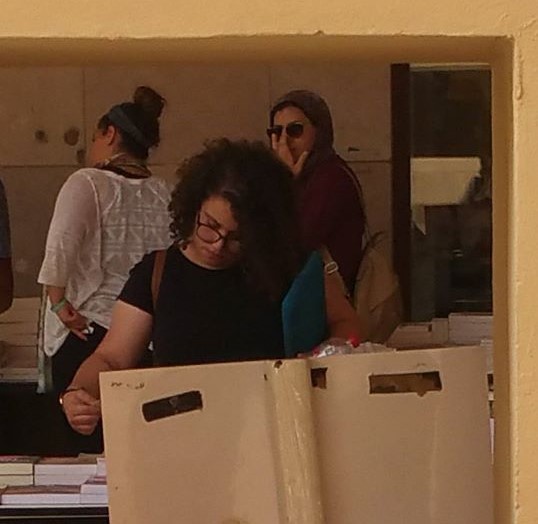 egyptian woman looking at books with two women in the background
